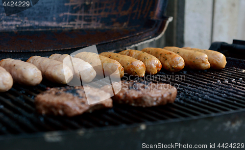 Image of Beefburgers and sausages cooking on an open grill