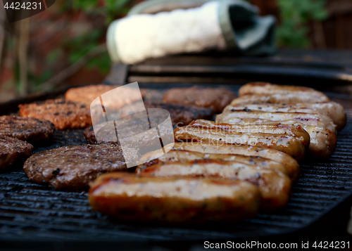 Image of Rows of sausages and hamburgers on a barbecue