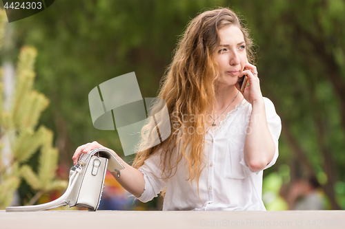 Image of Young girl with a handbag talking on the phone