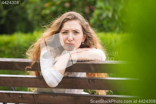 Image of A young girl sitting on a bench turned and looked ridiculously into the frame