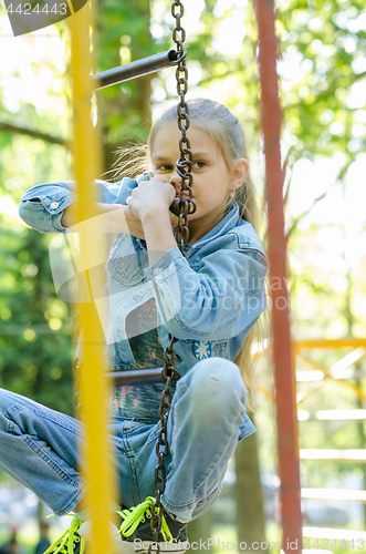 Image of The girl pondered climbed the hanging ladder in the playground