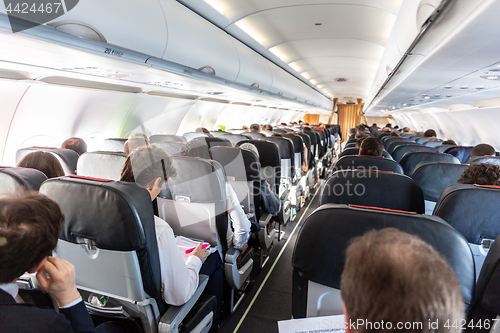 Image of Interior of large commercial airplane with passengers on their seats during flight.