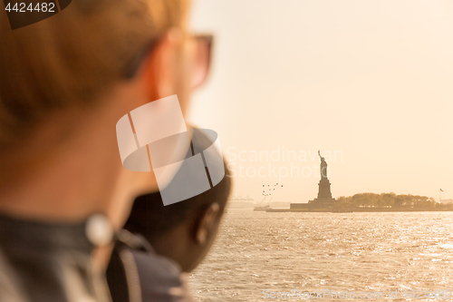 Image of Tourists looking at Statue of Liberty silhouette in sunset from the staten island ferry, New York City, USA
