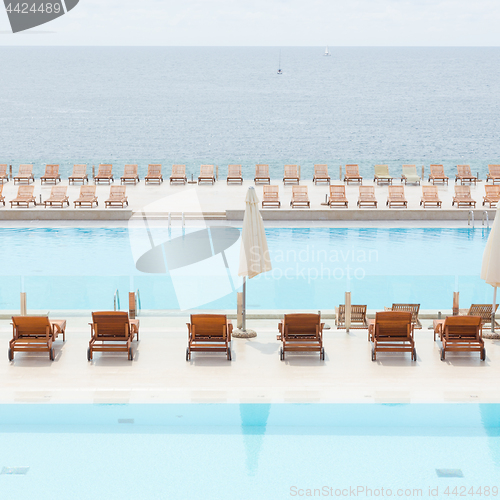 Image of Luxury swimming pool with wooden deck chairs.