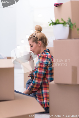 Image of woman with many cardboard boxes sitting on floor