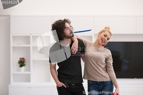 Image of couple in party hats blowing in whistle