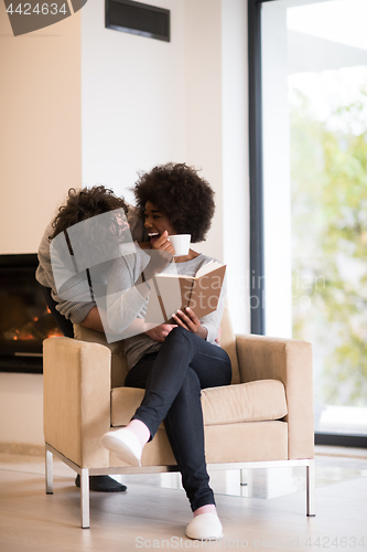 Image of multiethnic couple hugging in front of fireplace
