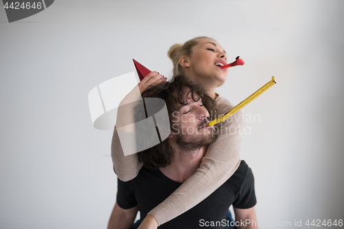 Image of couple in party hats blowing in whistle