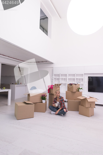 Image of woman with many cardboard boxes sitting on floor