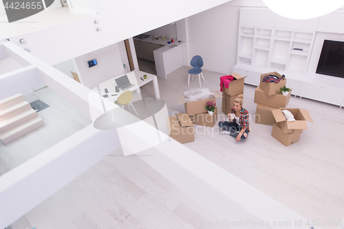 Image of woman with many cardboard boxes sitting on floor