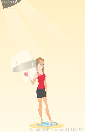 Image of Woman standing on scale and holding apple in hand.