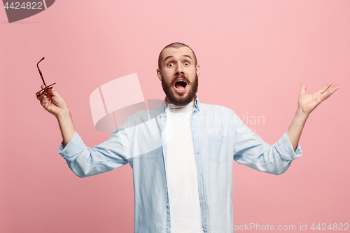 Image of The young attractive man looking suprised isolated on pink