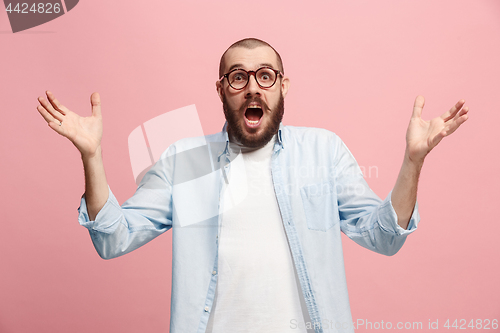 Image of The young attractive man looking suprised isolated on pink