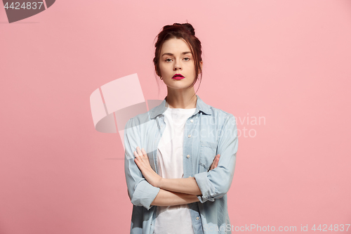 Image of The serious business woman standing and looking at camera against pink background.