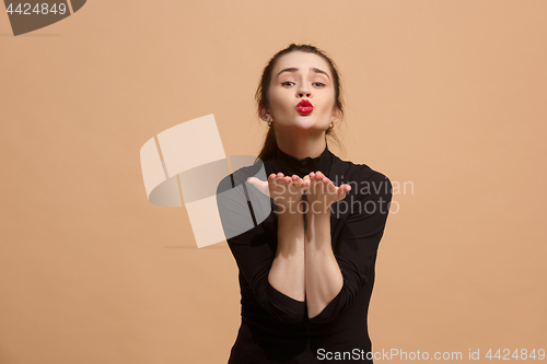 Image of Portrait of attractive cute girl with bright makeup sending kiss isolated over pastel background