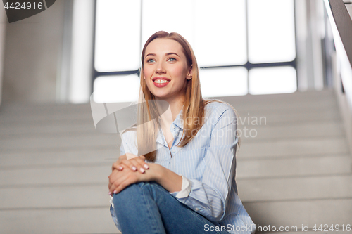 Image of happy smiling woman or student sitting on stairs