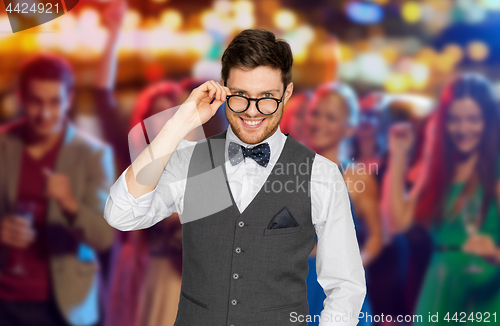 Image of man in suit and eyeglasses over night club party