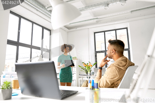 Image of woman showing tablet pc to creative team at office