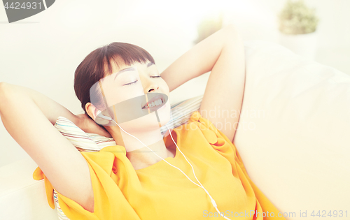 Image of happy asian woman with earphones listening music