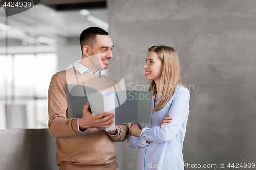 Image of man and woman with folders at office stairs