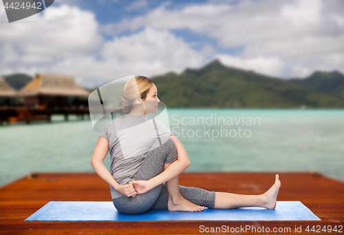 Image of woman making yoga in twist pose on mat outdoors