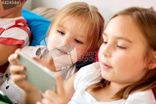 Image of little kids with smartphone in bed at home