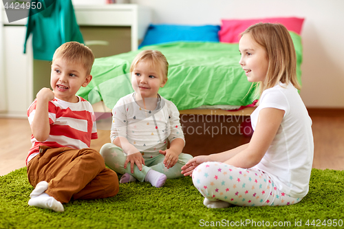 Image of group of happy kids sitting on floor at home