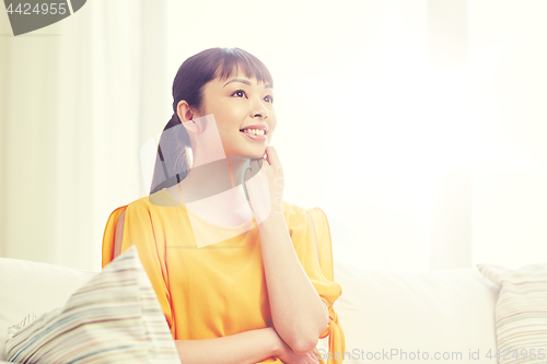 Image of happy asian young dreaming woman at home