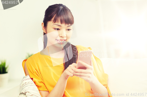 Image of happy asian woman with smartphone at home