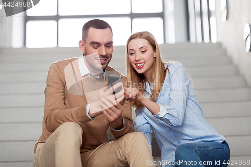 Image of man and woman with smartphone at office stairs