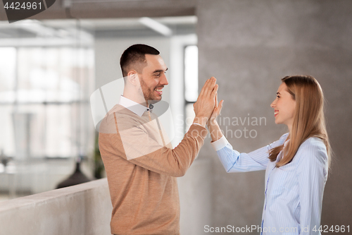 Image of man and woman making high five at office