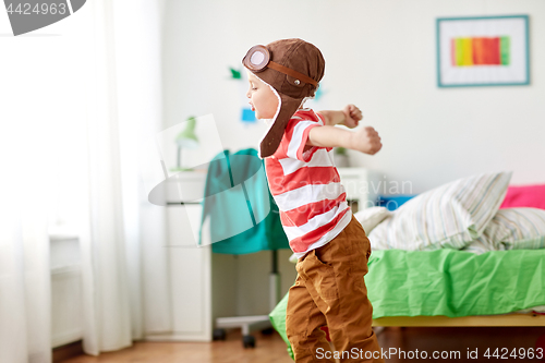 Image of happy little boy in pilot hat playing at home