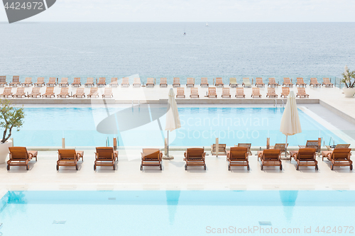 Image of Luxury swimming pool with wooden deck chairs.