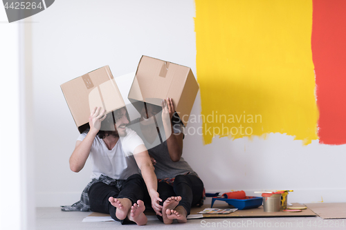 Image of young multiethnic couple playing with cardboard boxes