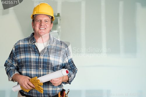 Image of Contractor with Plans and Hard Hat In Front of Drywall.