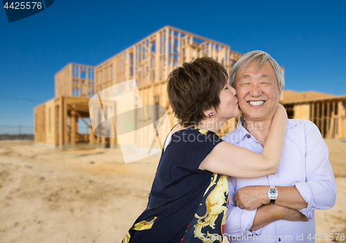 Image of Chinese Senior Adult Couple Kissing In Front Of New House Framin