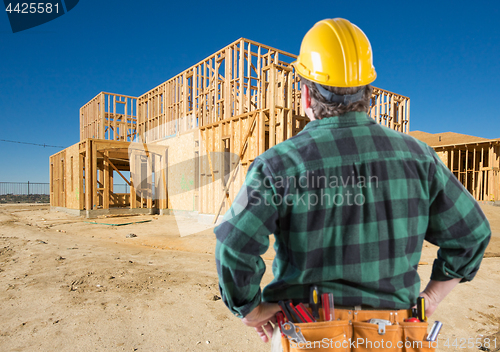 Image of Contractor with Hard Hat Looking At New House Framing at Constru