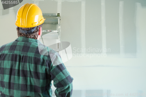 Image of Contractor in Hard Hat Looking at Drywall.