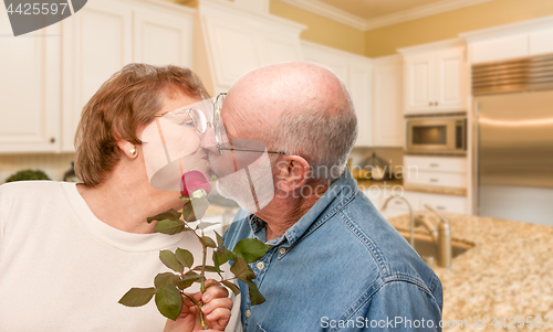 Image of Happy Senior Adult Man Giving Red Rose to His Wife Inside Kitche