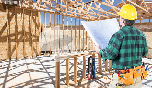 Image of Contractor with hard Hat and Plans Standing Inside Construction 