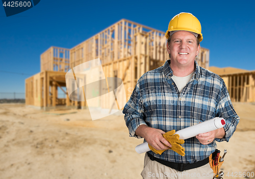 Image of Contractor with Plans and Hard Hat In Front of New House Framing