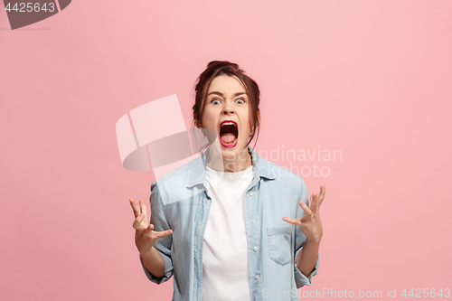 Image of The young emotional angry woman screaming on pink studio background