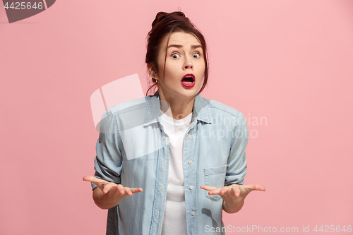 Image of Beautiful female half-length portrait isolated on pink studio backgroud. The young emotional surprised woman