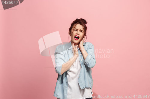 Image of The Ear ache. The sad woman with headache or pain on a pink studio background.
