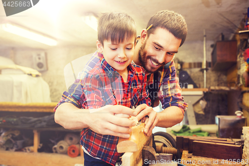 Image of father and son with plane shaving wood at workshop