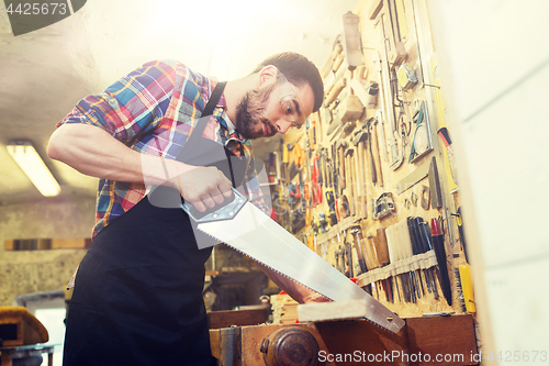 Image of carpenter working with saw and wood at workshop