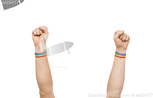 Image of hands with gay pride rainbow wristbands shows fist