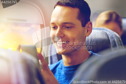 Image of happy man sitting in plane with smartphone