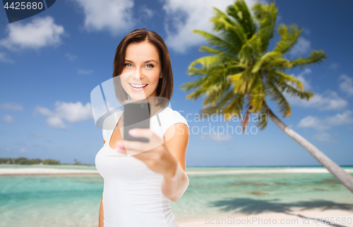 Image of woman taking selfie by smartphone on beach