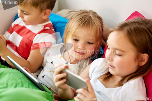 Image of little kids with smartphone in bed at home